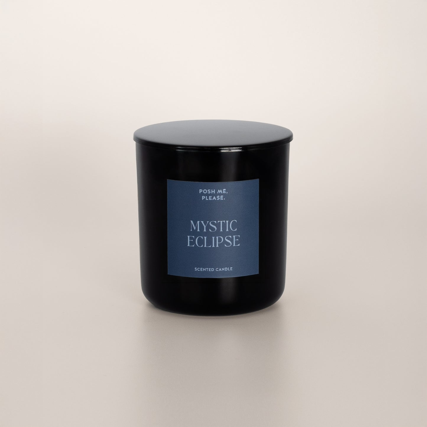 Mystic Eclipse black glass candle with blue-grey label by POSH ME, PLEASE., lid on, light background