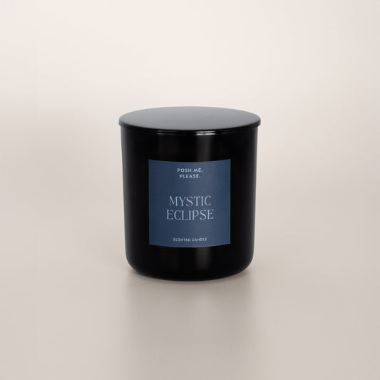Mystic Eclipse black glass candle with blue-grey label by POSH ME, PLEASE., lid on, light background