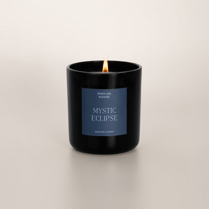 Lit Mystic Eclipse candle with flame, warm amber oriental scent, neutral background