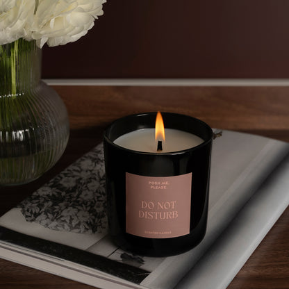 Lit Do Not Disturb candle on a dark tray with a journal, white flowers in glass vase, warm wooden background