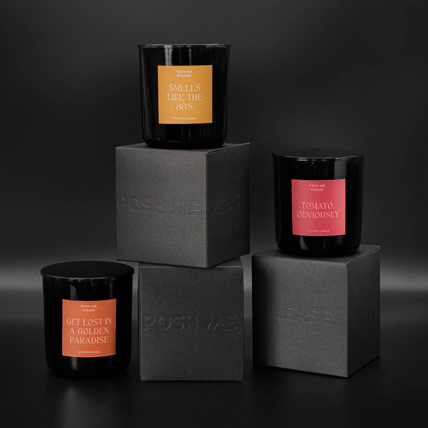 Smells Like The 80s, Tomato Obviously and Get Lost in a Golden Paradise candles stacked on embossed POSH ME, PLEASE. black blocks, dark background