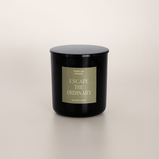 Escape the Ordinary black glass candle with olive green label by POSH ME,
PLEASE., lid on, light background