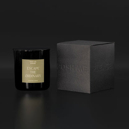 Escape the Ordinary candle beside black embossed POSH ME, PLEASE. gift box, dark background
