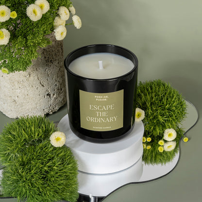 Escape the Ordinary candle unlit among green moss and white flowers on a marble tray, green background