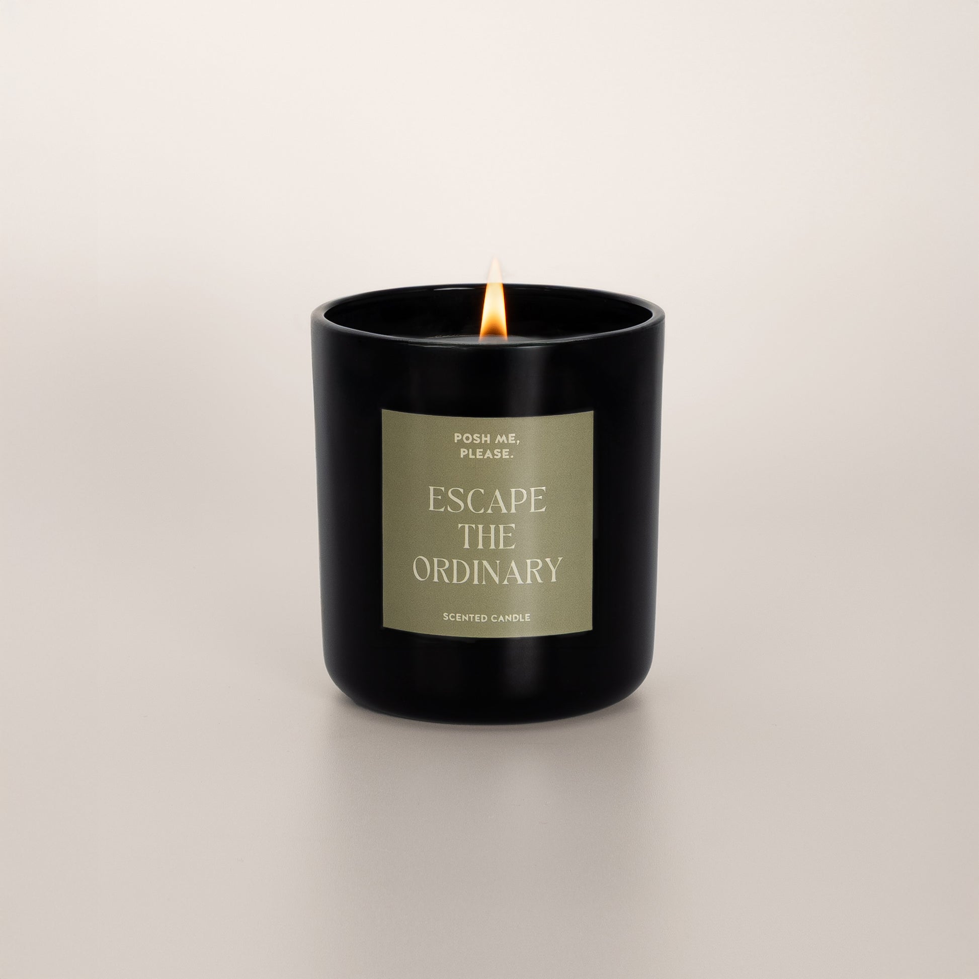 Lit Escape the Ordinary candle with flame, green floral scent, neutral background