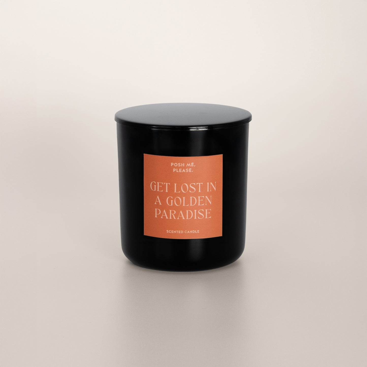Get Lost in a Golden Paradise black glass candle with copper label by POSH ME, PLEASE., lid on, light background
