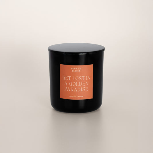Get Lost in a Golden Paradise black glass candle with copper label by POSH ME, PLEASE., lid on, light background
