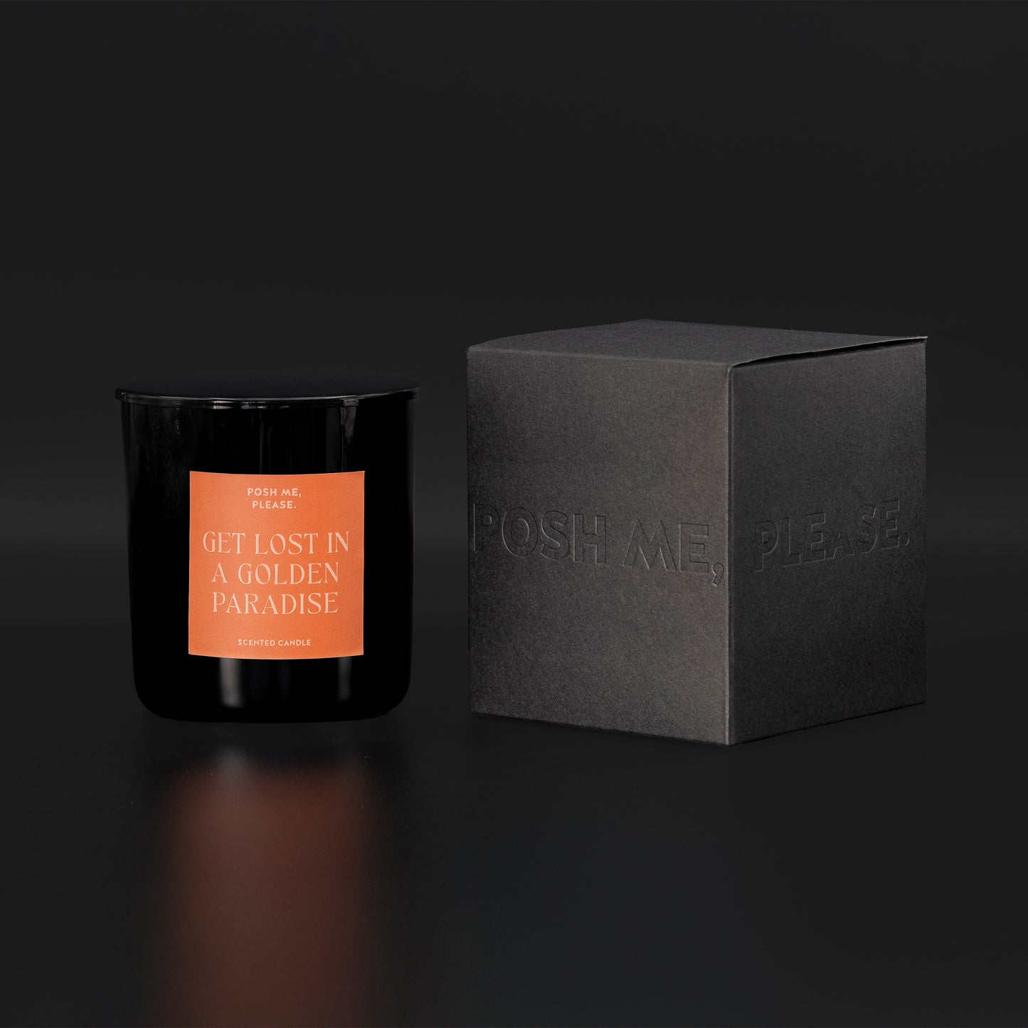 Get Lost in a Golden Paradise candle beside black embossed POSH ME, PLEASE. gift box, dark background