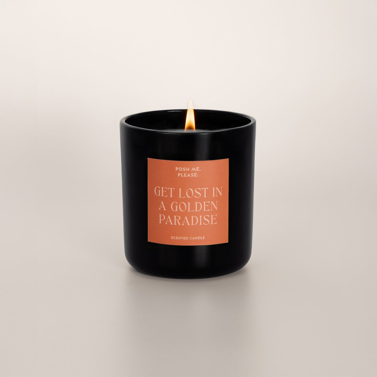 Lit Get Lost in a Golden Paradise candle with flame, pear agave vanilla scent, neutral background