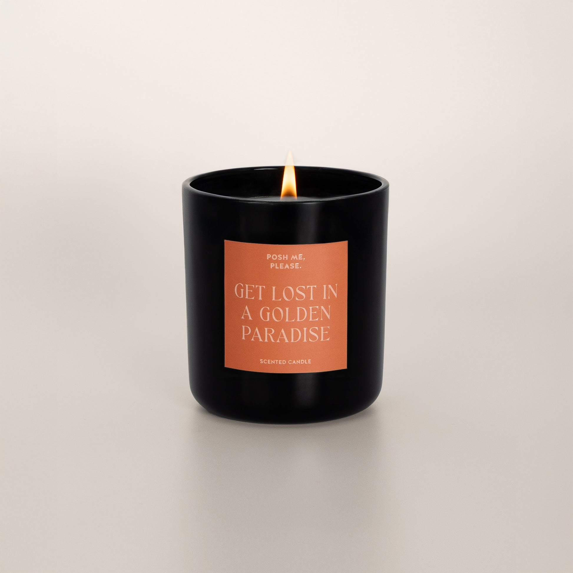 Lit Get Lost in a Golden Paradise candle with flame, pear agave vanilla scent, neutral background