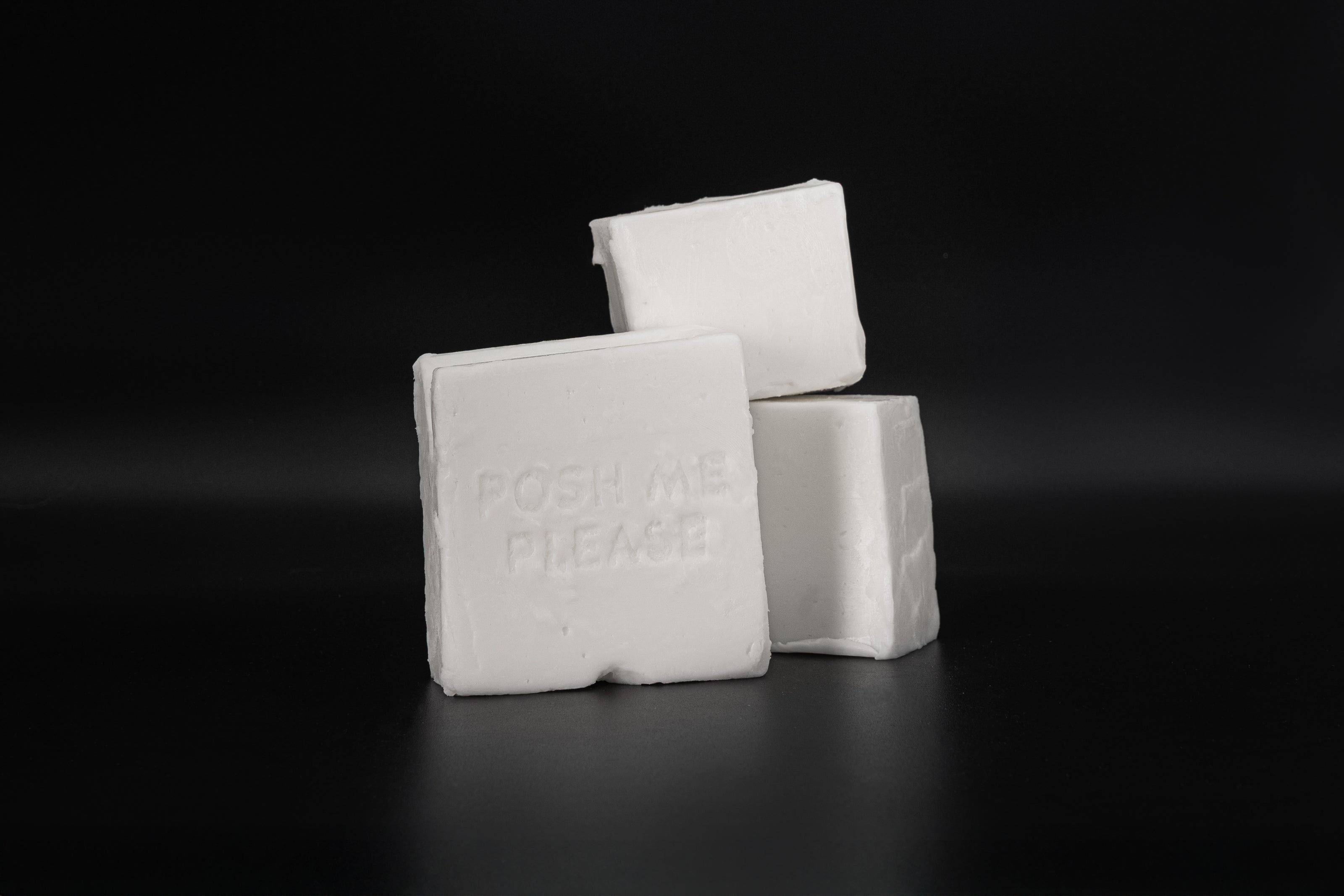 White coconut wax blocks with embossed POSH ME, PLEASE. text, dark background