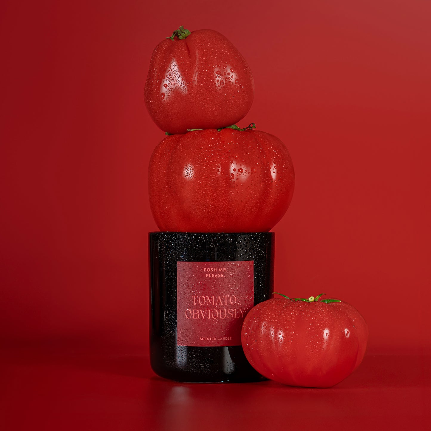Tomato, Obviously candle surrounded by stacked red tomatoes against a deep red
background