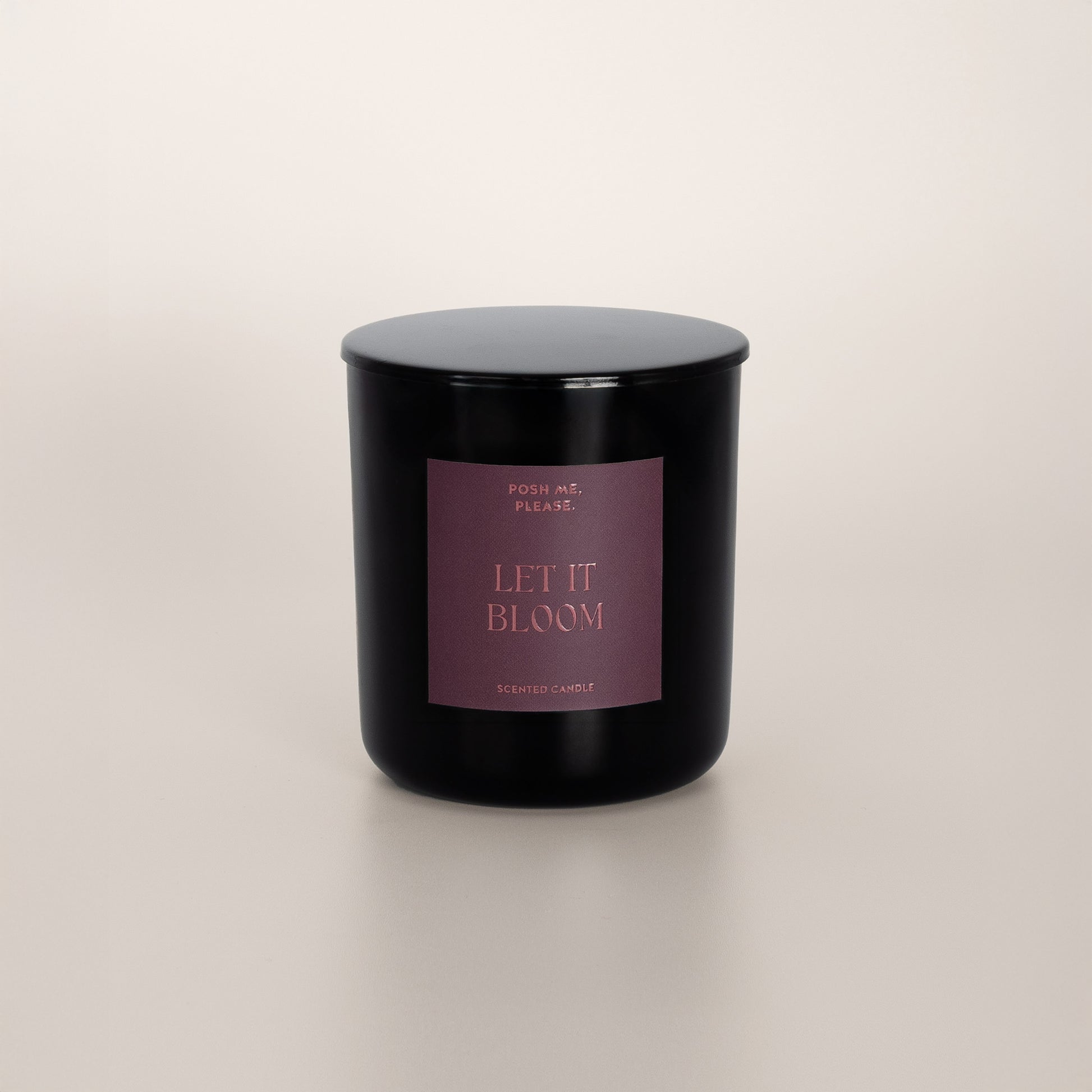 Let It Bloom black glass candle with dusty rose label by POSH ME, PLEASE., lid on, light background