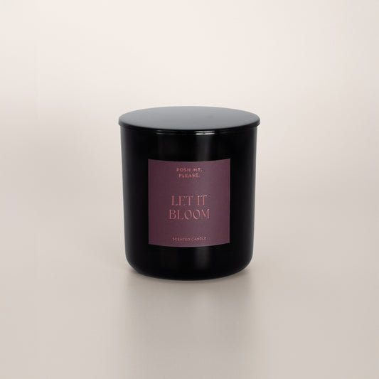 Let It Bloom black glass candle with dusty rose label by POSH ME, PLEASE., lid on, light background